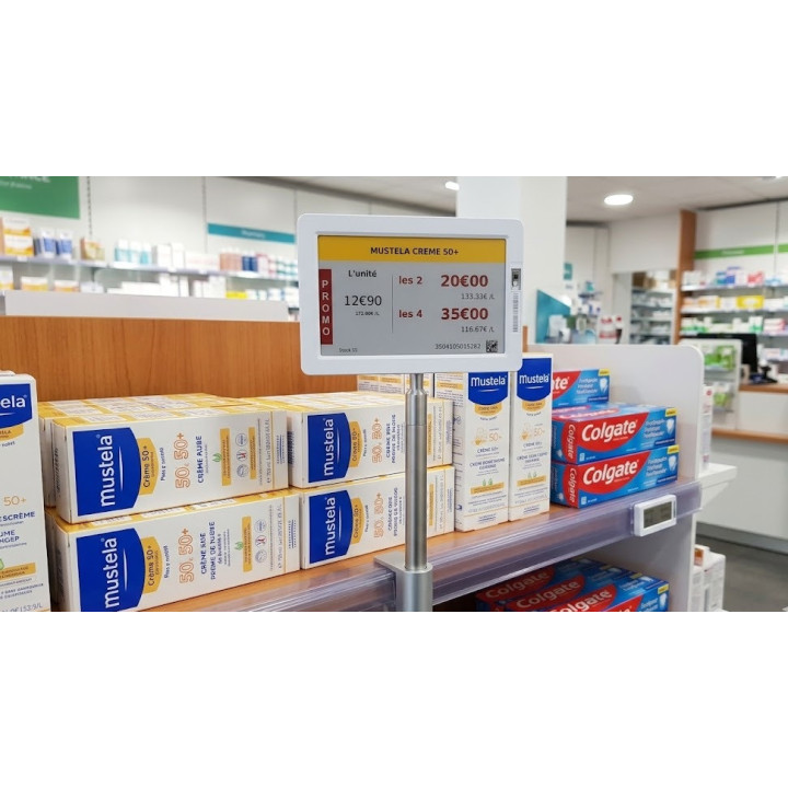 Une grande étiquette électronique de promotion Mustela montée sur un mât métallique fixé à une étagère de pharmacie